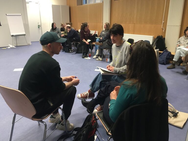 Drei Menschen sitzen zusammen und sprechen in einer Kleingruppe